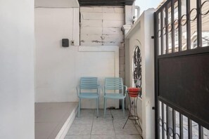 A narrow outdoor area with two chairs, a metal gate, and a tiled floor. - Spacious Family Haven Chatuchak Market - 5BR House (Bangkok)
