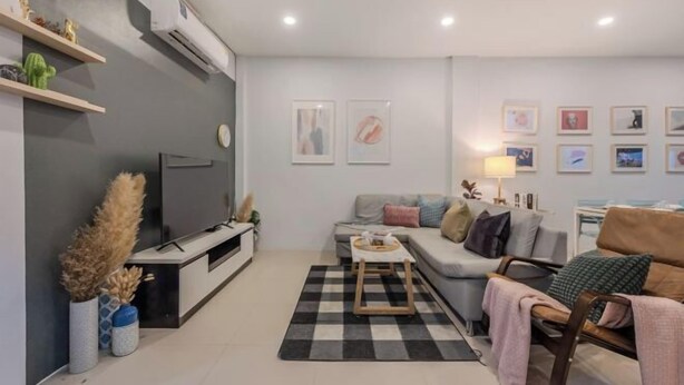 Un salon moderne avec un canapé, une table basse, un téléviseur et des œuvres d’art accrochées aux murs.