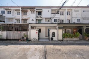 A multi-story residential building with a covered entrance, potted plants, and a visible garage door. - Spacious Family Haven Chatuchak Market - 5BR House (Bangkok)