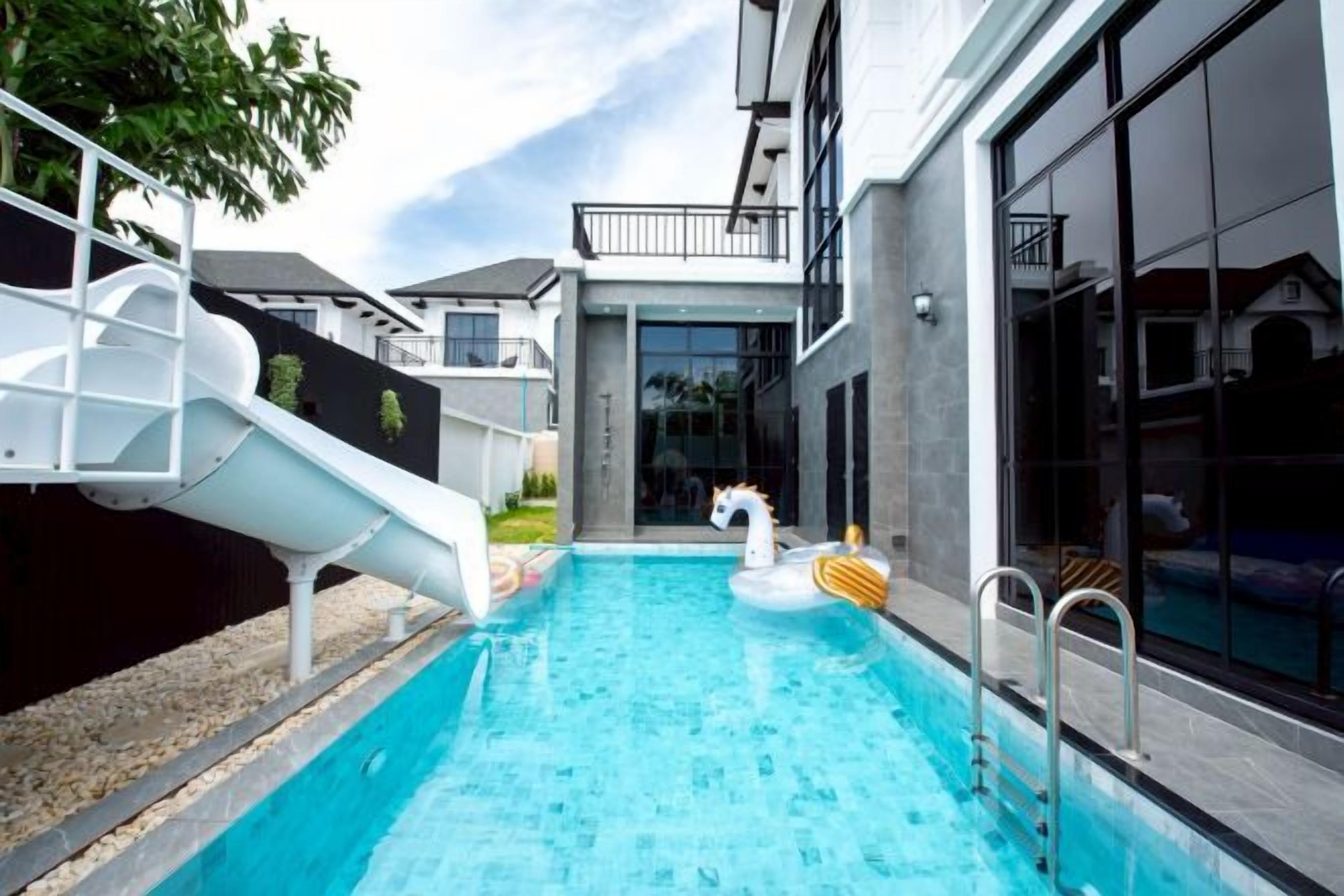 A swimming pool with a slide and inflatable swan floatation device.