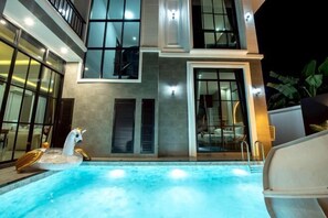 Un edificio moderno con piscina, ampie finestre e un balcone.