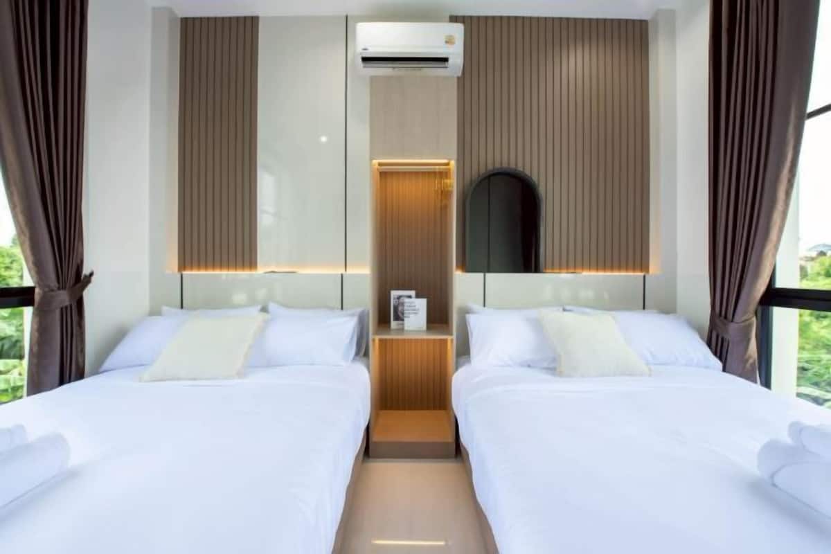 Une chambre d’hôtel avec deux lits, un système de climatisation central, une petite table et un miroir.