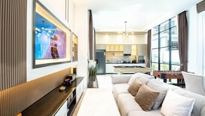 A modern living room with a sofa, a coffee table, and a TV mounted on the wall. - Modern 3BR British Pool Villa + 5KM Jomtien Beach (Pattaya)