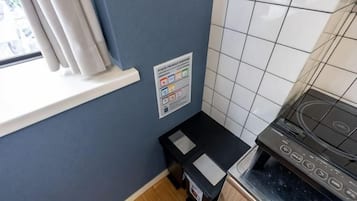 A kitchen with a stove, a window with curtains, and a tiled backsplash.