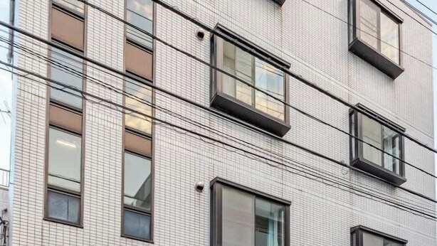 A multi-story building with a tiled facade and rectangular windows. - Guest House IROHA (Tokyo)