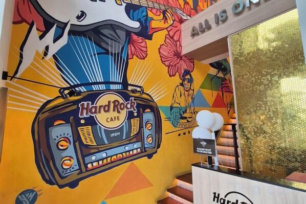 A Hard Rock Cafe with a vibrant mural, a radio, and a staircase.