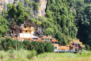 A traditional building with multiple levels, surrounded by lush greenery and a steep cliff.