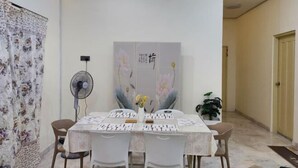 A dining area with a table set for four, a fan, and a decorative wall piece. - Ipoh Homestay Vacation 12 Pax 4 Bedroom for Delicious Food (Ipoh)