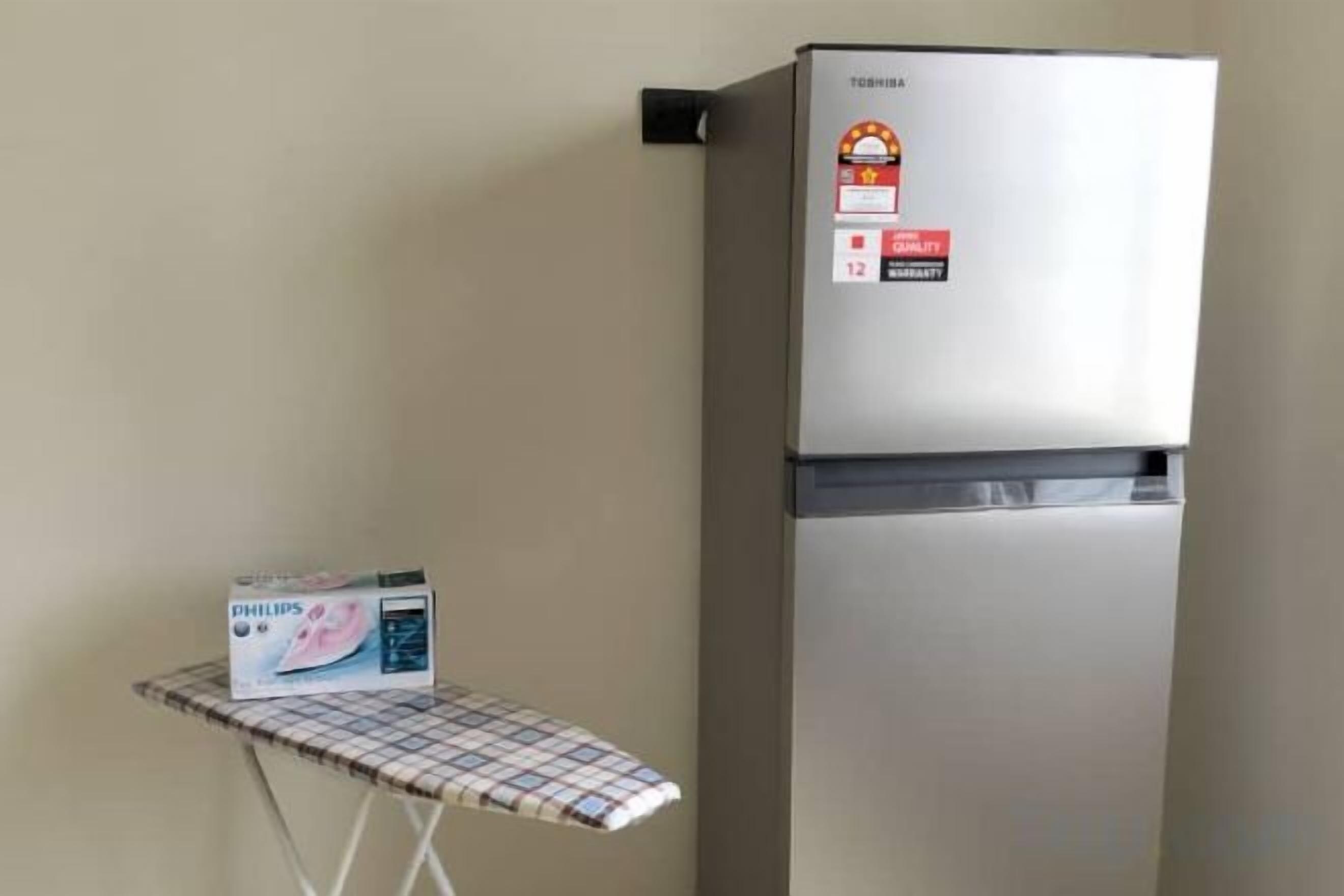 A refrigerator with a control panel and a box of Philips brand products on an ironing board.