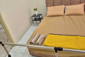 A bed with a brown headboard, a small table with a vase of flowers, and a yellow blanket. - Ipoh Homestay Vacation 12 Pax 4 Bedroom for Delicious Food (Ipoh)