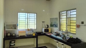 A kitchen with a black countertop, white cabinets, a microwave, a kettle, and a sink. - Ipoh Homestay Vacation 12 Pax 4 Bedroom for Delicious Food (Ipoh)