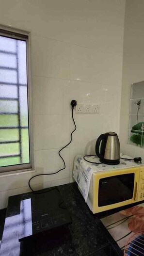 A kitchen with a microwave, kettle, and a power strip on the counter. - Ipoh Homestay Vacation 12 Pax 4 Bedroom for Delicious Food (Ipoh)