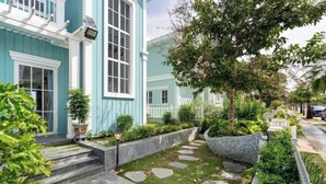 A residential property with a blue exterior, a stone pathway, and a well-maintained garden.