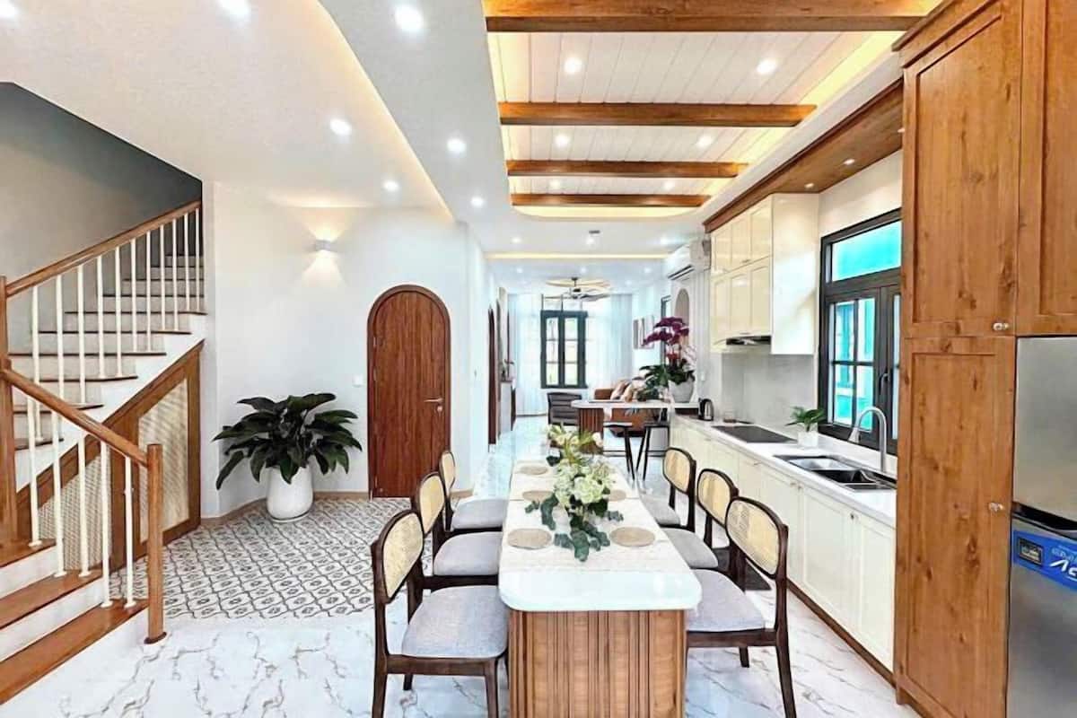 A modern kitchen with white cabinets, a wooden dining table, and a built-in oven.