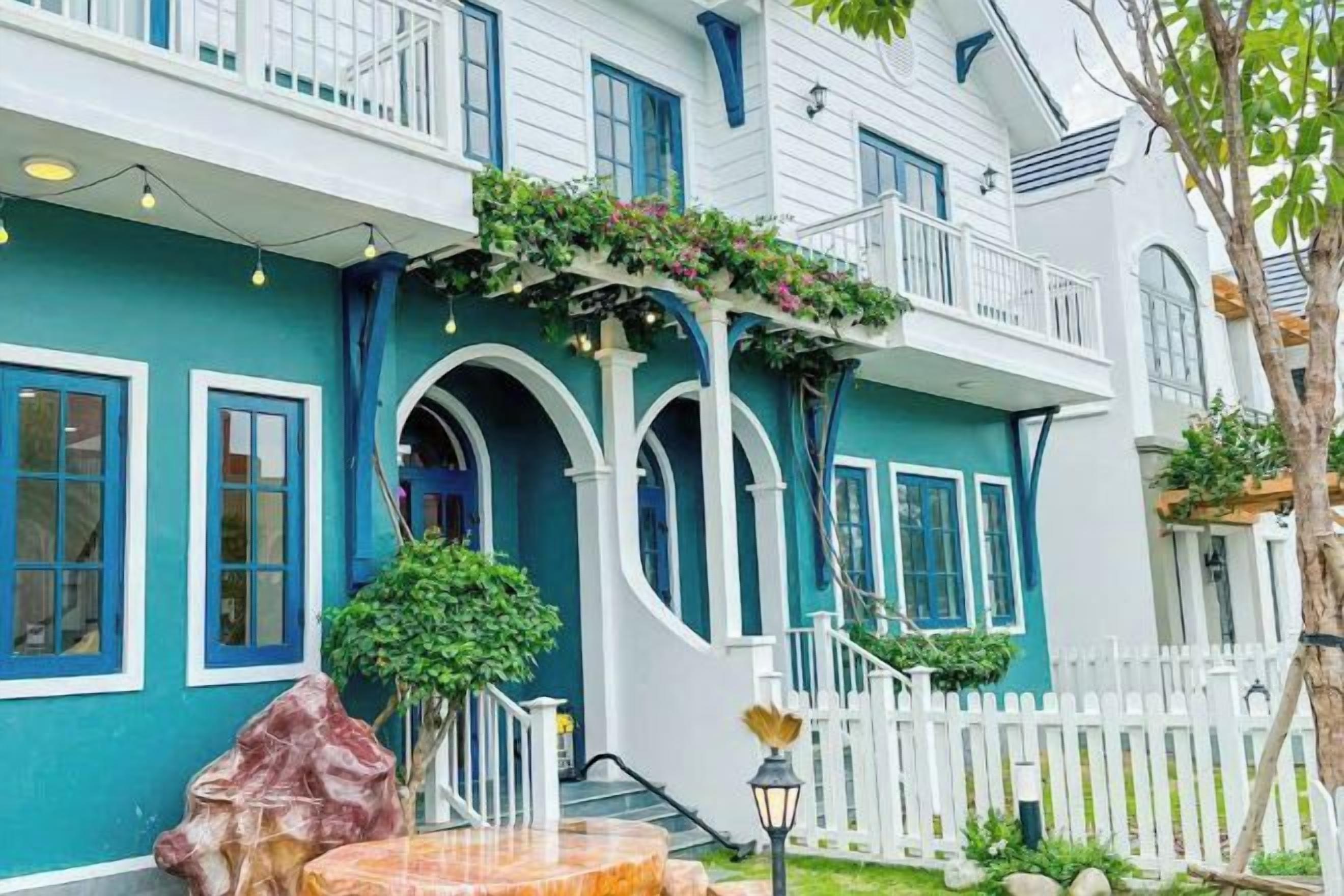 A two-story building with a white exterior, blue trim, and a white picket fence.