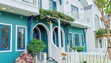 A two-story building with a white exterior, blue trim, and a white picket fence.