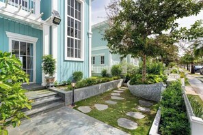 Una propiedad residencial con un jardín bien cuidado, un sendero de piedra y una casa azul con detalles blancos.