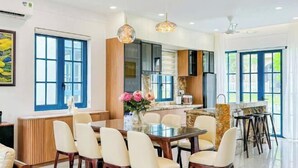 A modern kitchen with a dining area, large windows, and a marble island.