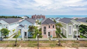 A residential area with houses, a white picket fence, and a view of the ocean.
