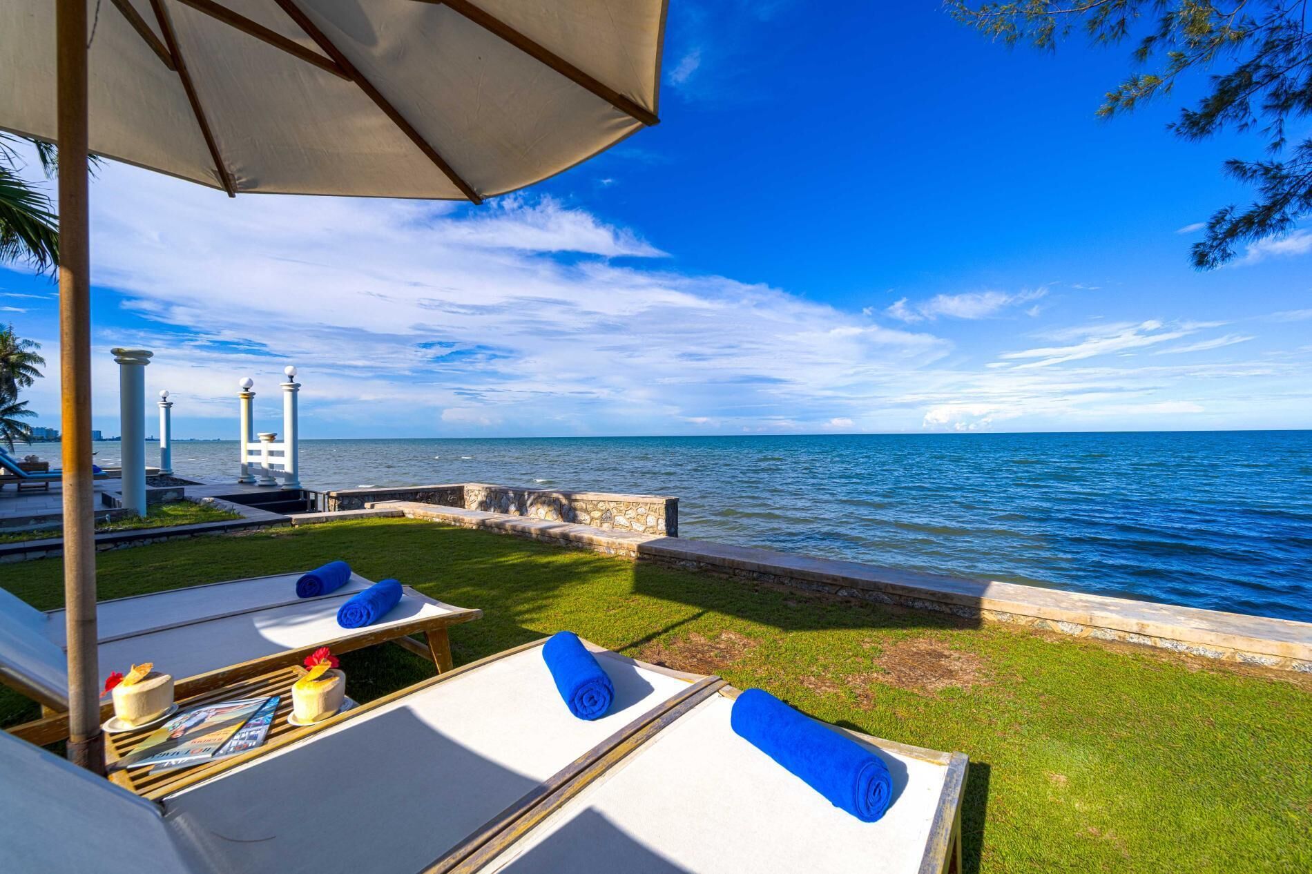 Eine Seeterrasse mit Liegestühlen, einem Tisch mit Zeitschriften und Kuchen sowie Blick aufs Meer.