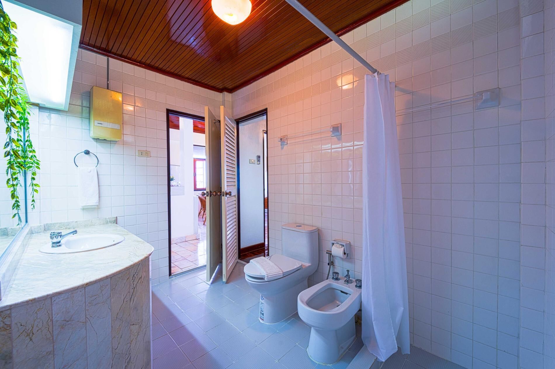 A bathroom with a marble sink, two toilets, a bidet, and a shower curtain.