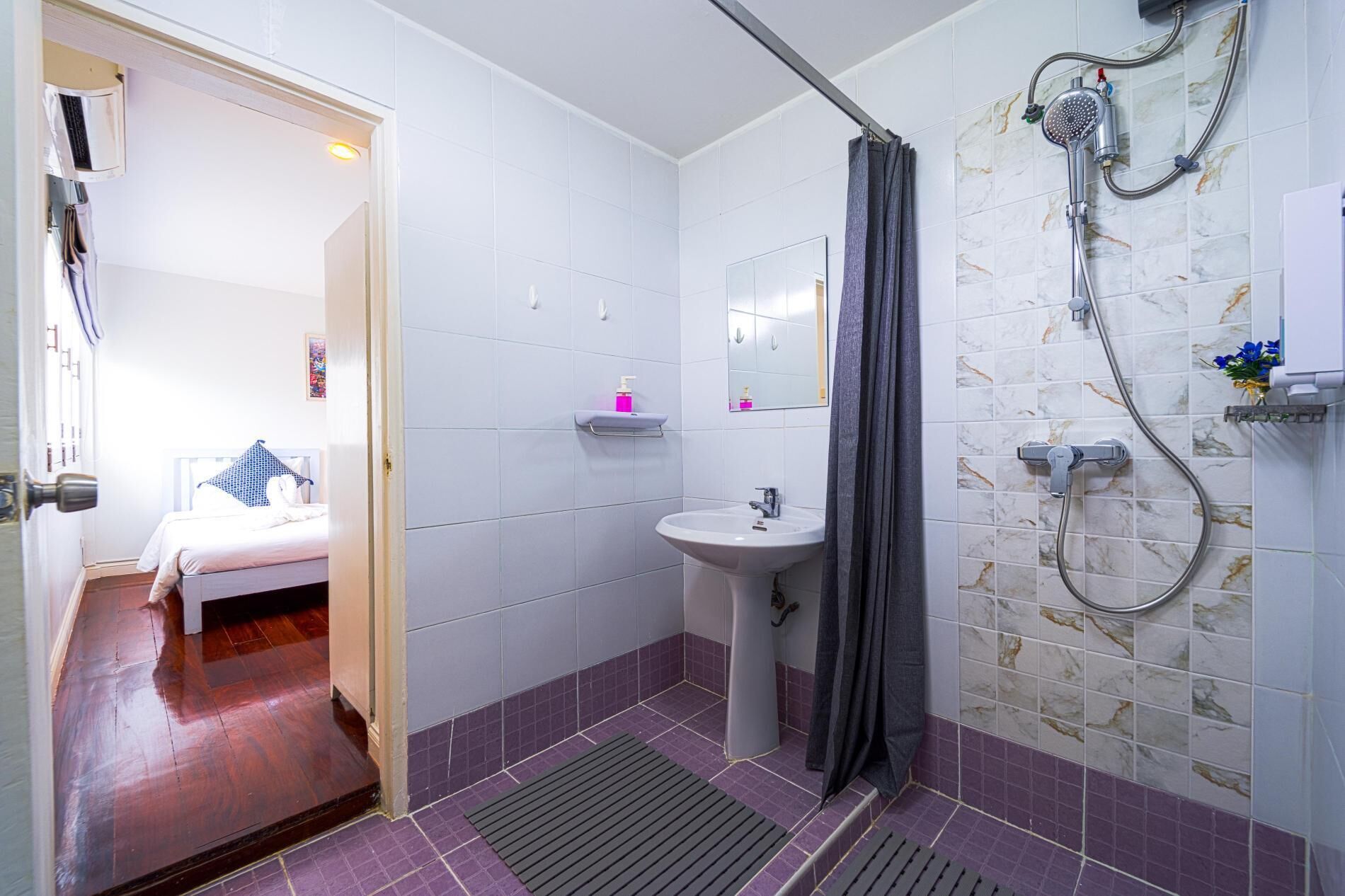 A small, compact bathroom with a shower, a sink, and a mirror.