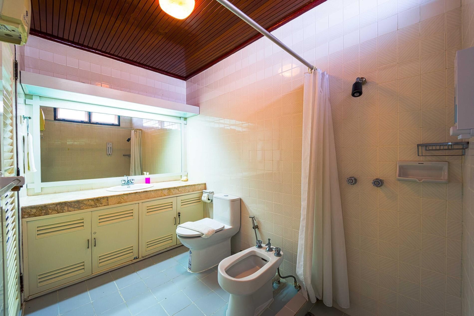 A bathroom with a toilet, bidet, sink, and mirror.
