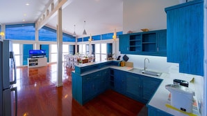 A modern kitchen with blue cabinets, a large island, and a dining area with a view.