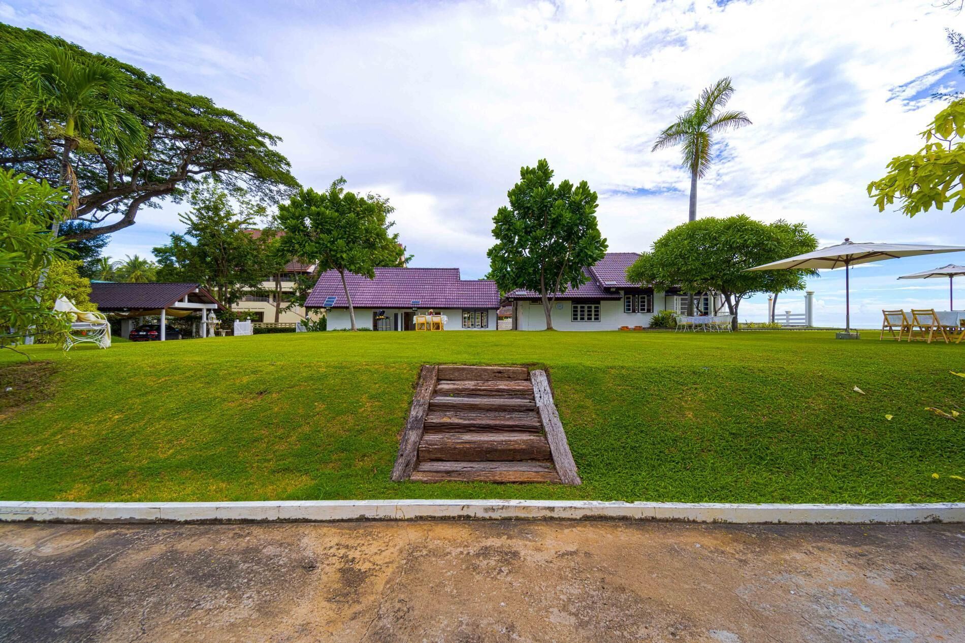 A residential property with a grassy lawn, a wooden deck, and a house with a purple roof.