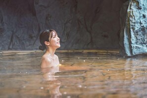 Une personne se trouve dans une étendue d’eau, avec un sol en pierre et un arrière-plan évoquant une grotte.