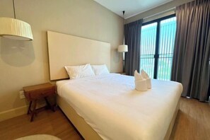 Een hotelkamer met een groot bed, nachtkastje, lamp en uitzicht op het omliggende landschap.