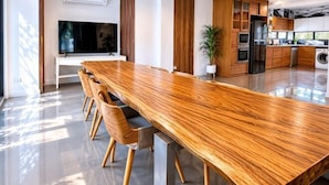 Una cucina moderna con un lungo tavolo di legno, elettrodomestici integrati e un'ampia finestra.