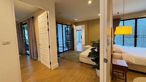 Una camera d'albergo con un letto, un tavolino, una pianta e vista sull'esterno.