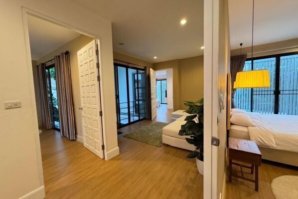 A hotel room with a bed, a small table, a plant, and a view of the outside. - Monte Villa Chiang Mai (San Sai)
