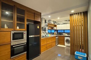 A modern kitchen with built-in appliances, wooden cabinetry, and a marble backsplash. - Monte Villa Chiang Mai (San Sai)