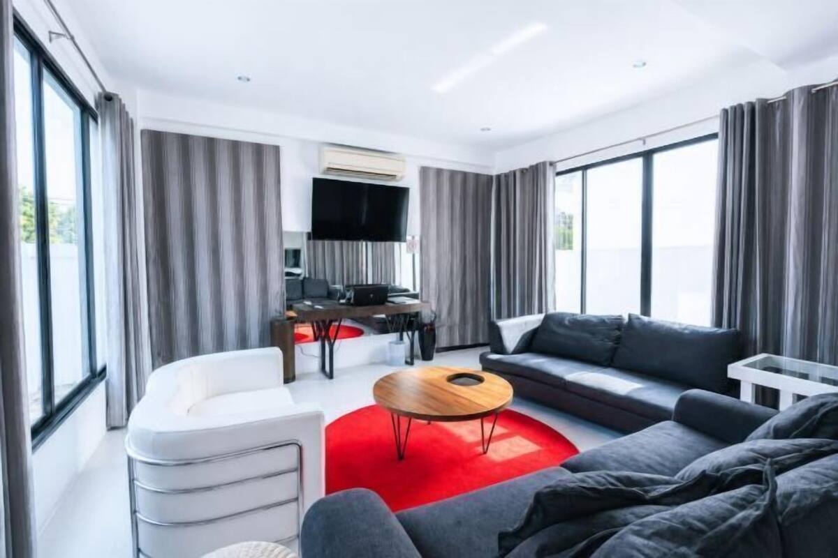 Ein modernes Wohnzimmer mit einer Couch, einem Couchtisch, einem Fernseher und einem Schreibtisch.