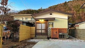 Une maison de plain-pied avec une porte d’entrée, un petit porche et une cour arrière clôturée.
