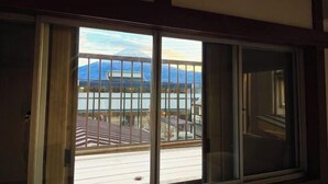 Une pièce dotée d’une porte-fenêtre coulissante donnant sur un balcon avec vue sur les montagnes et un bâtiment.