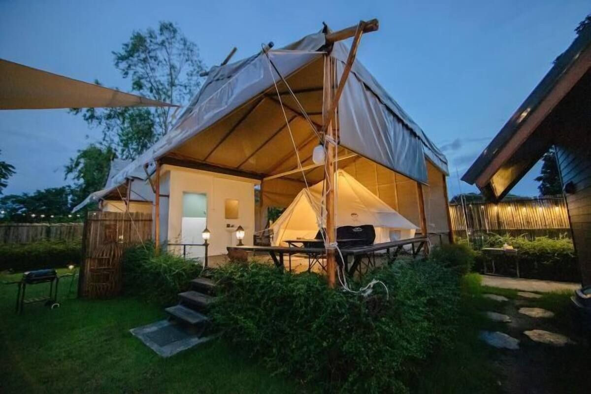 A tented accommodation with a patio area, steps leading to the entrance, and a small table with chairs.