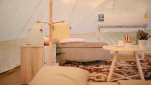 A cozy interior with a bed, a small table, a kettle, and a plant. - With You Camp (Sirindhorn)