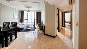 A modern living room with a dining table, sofa, and a large window. - Large and Strategic Rasuna Apt 3BR with WiFi &Pool (South Jakarta)