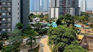 A high-rise residential building with a pool area surrounded by greenery. - Large and Strategic Rasuna Apt 3BR with WiFi &Pool (South Jakarta)