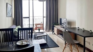 A modern living room with a dining area, large windows, and a balcony. - Large and Strategic Rasuna Apt 3BR with WiFi &Pool (South Jakarta)