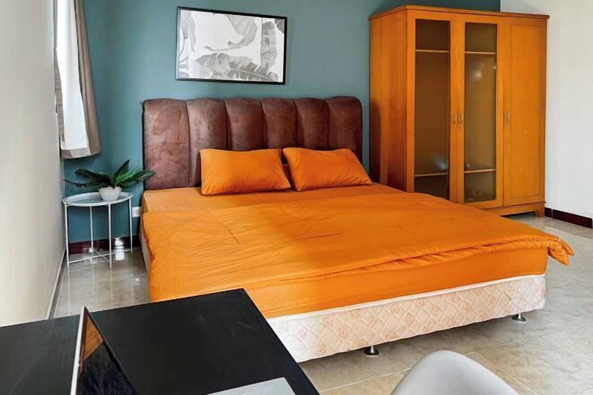 A bedroom with a bed, a nightstand, a cabinet, and a wall-mounted artwork.