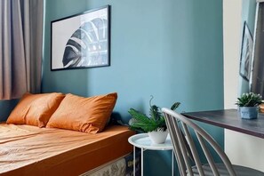 A bedroom with a bed, pillows, a small table with a plant, and a chair. - Large and Strategic Rasuna Apt 3BR with WiFi &Pool (South Jakarta)