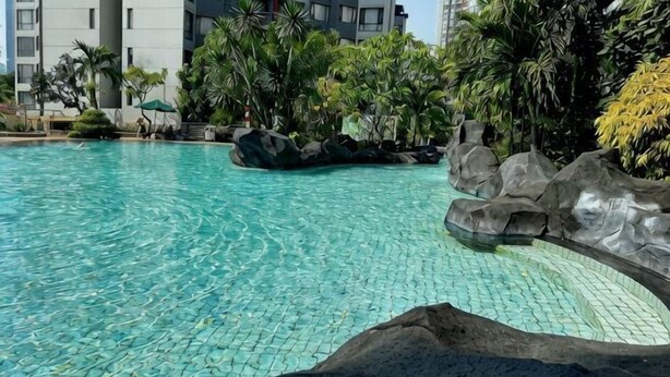 A swimming pool with clear water, surrounded by rocks and greenery. - Large and Strategic Rasuna Apt 3BR with WiFi &Pool (South Jakarta)