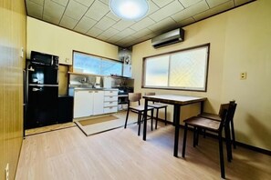 A compact kitchen with a refrigerator, stove, and microwave. There is a dining table with chairs and a window with a view. - Kaze No Ya (Shirahama)