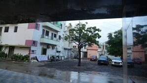 A residential street with houses, a tree, and parked cars. - Hotel The Grand Om Krishna (Dwarka)