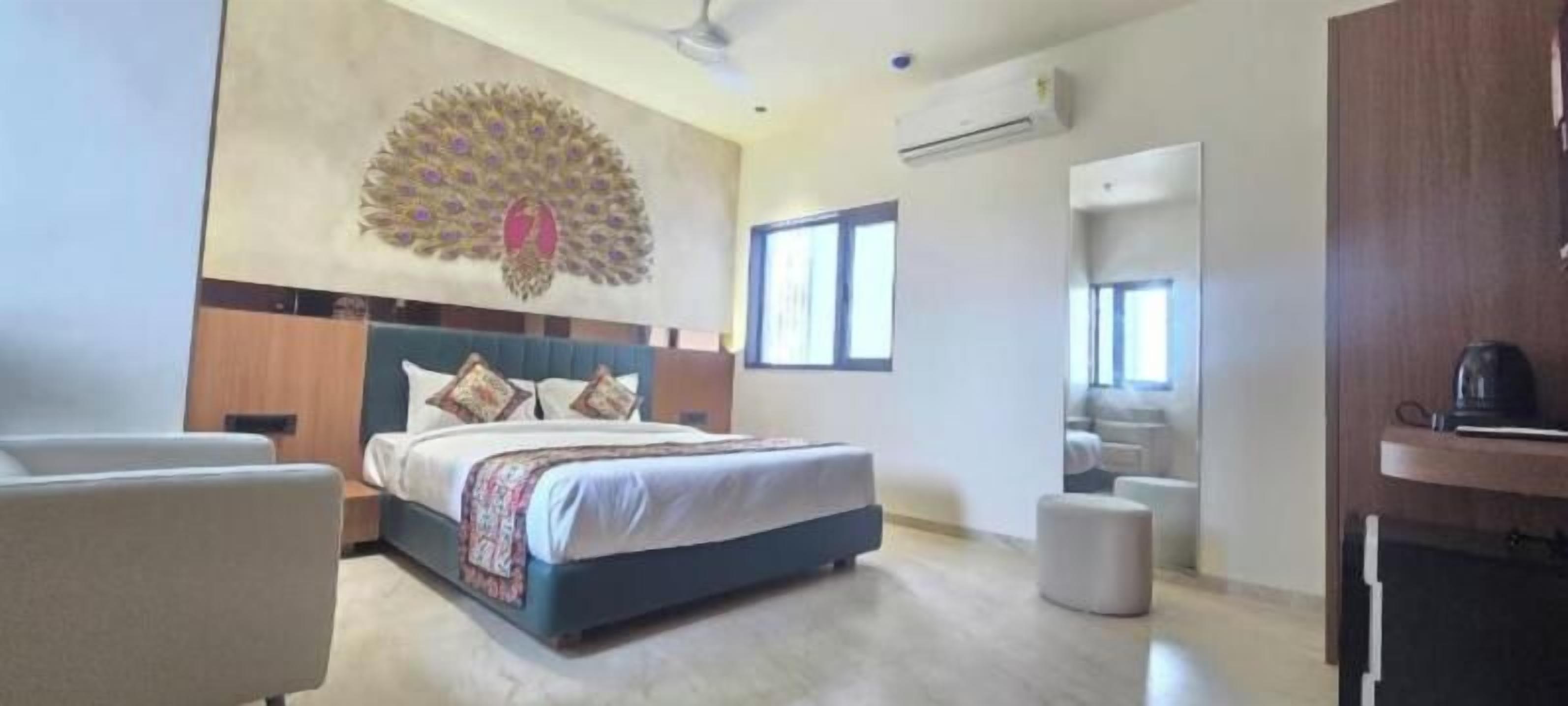 Un dormitorio con una cama, una silla, un tocador y una decoración de pared con motivos de pavo real.