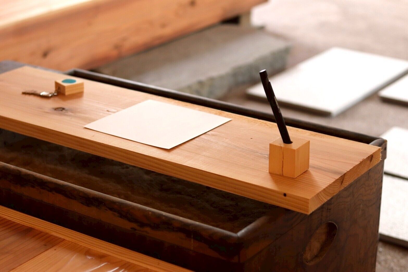 Ein Holztisch mit Papier, Stift und einem kleinen Holzklotz.
